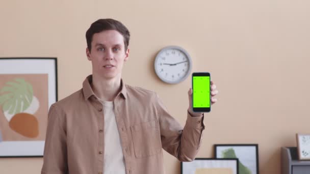 若い白人男性のPOVを待って,屋内で立っているカメラでスマートフォンディスプレイを表示 - 映像、動画