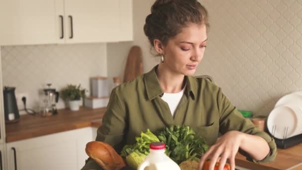 若い白人女性は,食料品の配達サービスによって配達された段ボール箱から新鮮な果物や野菜を取ります - 映像、動画