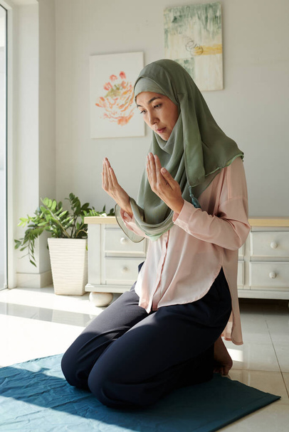 Moslimvrouw in hijab biddend thuis, geloof en spiritualiteit concept - Foto, afbeelding