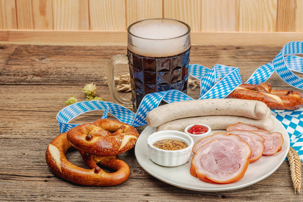 Tradycyjny zestaw Oktoberfest. Precle, piwo, weisswurst i eisbein z musztardą. Niemiecki festiwal żywności koncepcja. Modne drewniane tło, przestrzeń do kopiowania - Zdjęcie, obraz