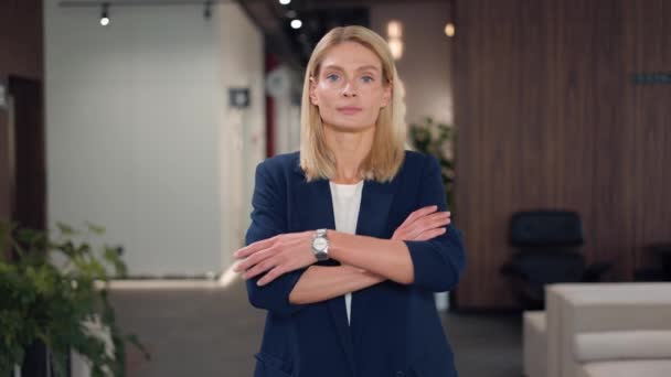 Successful caucasian woman posing with crossed hands in corporate office. Confident female manager with charming appearance dressed in formal office clothes standing and smiling sincerely. - Footage, Video