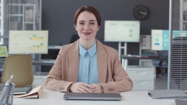 Taille omhoog POV van jonge Kaukasische vrouw zittend aan bureau in hedendaags kantoor sprekend op camera het geven van zakelijk advies aan cliënt - Video