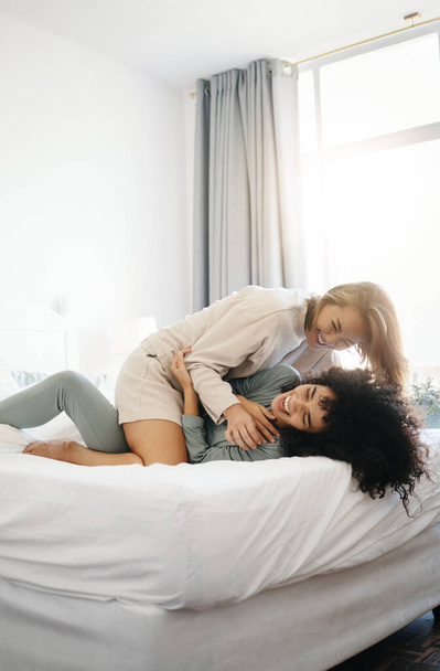 Mutlu, gülen ve sabah yatak odasında sevişmek ve kaynaşmak için lezbiyen bir çift. Ev, romantizm ve gay ya da Igbt kadınları sohbet etmek, gıdıklanmak ve evde rahat etmek için bir yataktalar.. - Fotoğraf, Görsel