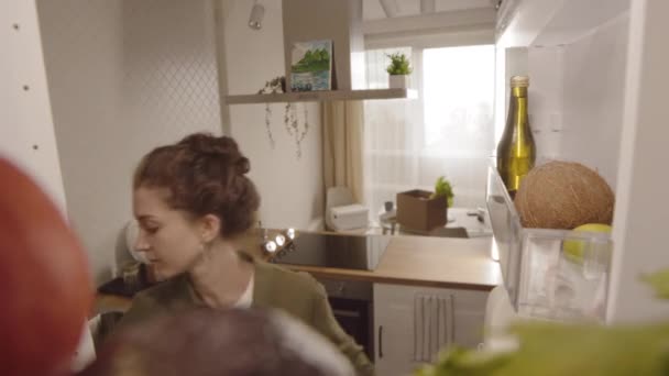 POV belül hűtőszekrény lövés a fiatal gyönyörű kaukázusi nő figyelembe, és forgalomba élelmiszer-ipari termékek hűtőszekrényben otthon - Felvétel, videó