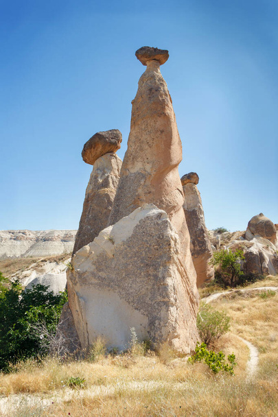 Unikátní geologické skalní útvary Vílí komíny v Cappadocii proti modré obloze v létě. Oblíbená turistická oblast v Goreme, Nevsehir, Turke - Fotografie, Obrázek
