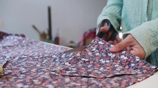 Kobieta ostrożnie wycina wzory z kwiatowej tkaniny nożyczkami. Środek strzału - Materiał filmowy, wideo