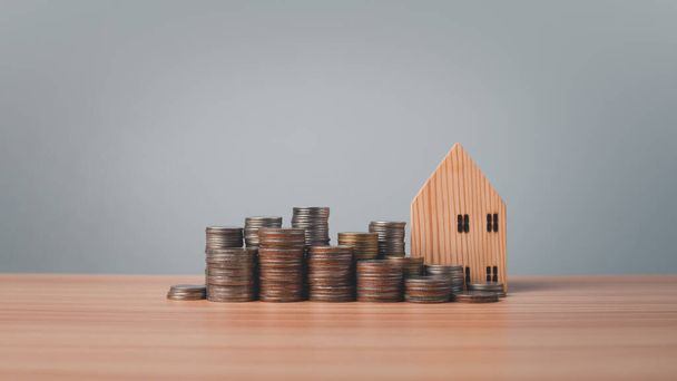 Modell Holzhaus und Münzen reihen sich auf Holzboden auf weißem Hintergrund aneinander. Konzepte von Finanzen, Ersparnissen und Investitionen. Immobilienkonzepte. - Foto, Bild