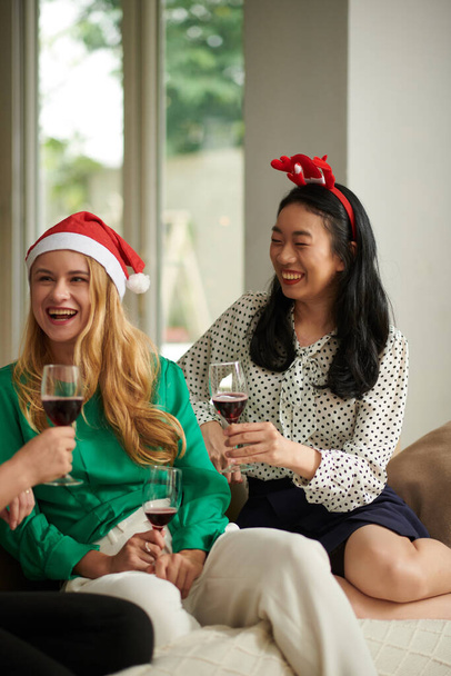 Cheerful female colleagues gathered at home after work for small Christmas party - Photo, Image
