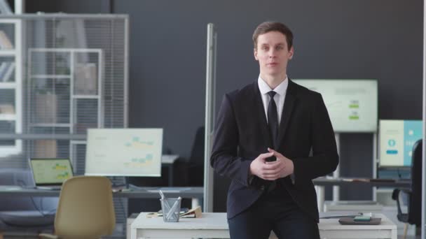 Média POV tiro de jovem empresário caucasiano confiante em formalwear olhando para câmera fazendo apresentação de pé no escritório moderno com gráficos de negócios e gráficos em telas de computador - Filmagem, Vídeo