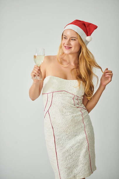 Retrato de jovem mulher em chapéu de Papai Noel holsing copo de champanhe - Foto, Imagem