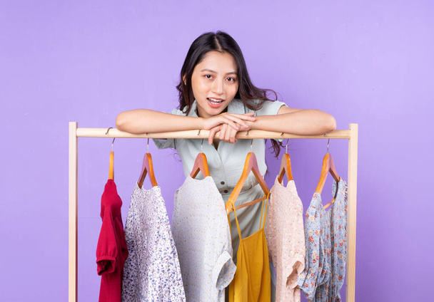 Immagine di donna di moda in gonna in piedi vicino armadio con vestiti e la scelta di cosa indossare isolato su sfondo viola - Foto, immagini