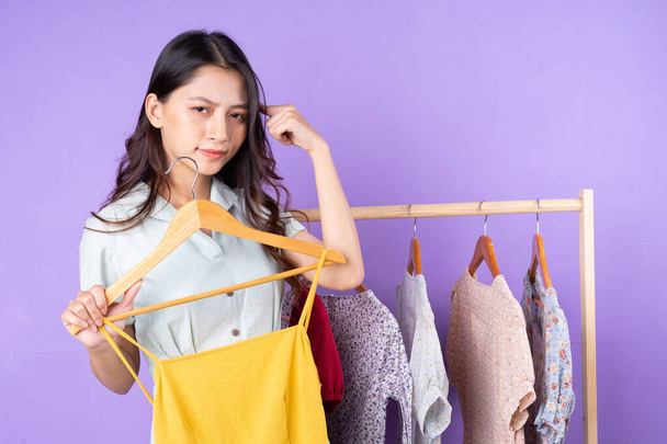 Image of fashion woman in skirt standing near wardrobe with clothes and choosing what to wear isolated on purple background - Photo, Image