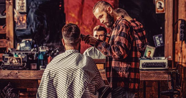 Man visiting hairstylist in barbershop. Barber works with hair clipper. Hipster client getting haircut. Bearded man in barbershop. Haircut concept. - Photo, Image