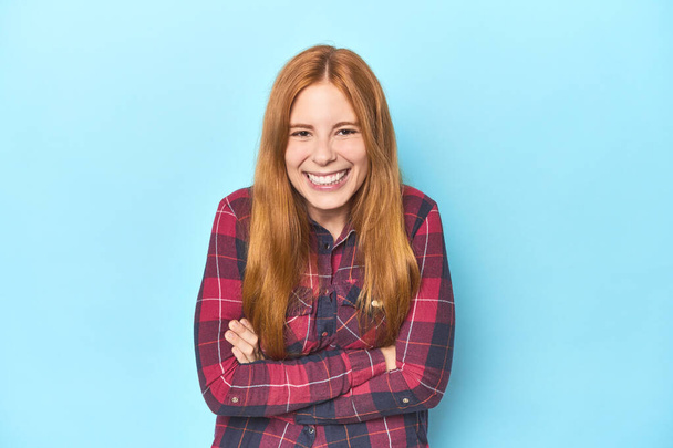 Redhead young woman on blue background laughing and having fun. - Photo, Image