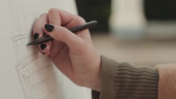Крупный план руки черно-гвоздичной художницы, рисующей башню с карандашом на улице - Кадры, видео
