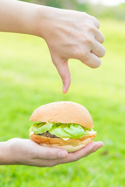 Mulher mão segurando hambúrguer e não gosta de fast food
 - Foto, Imagem