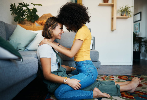 Lgbtq, couple and love with hug on a living room floor in new home with smile of lesbian women. Gay marriage, happy and together with care and support in a lounge with embrace sitting on the ground. - Photo, Image
