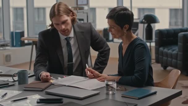 Waist up van jonge Kaukasische zakenman overleg met vrouwelijke advocaat over zakelijke contract staat hij op het punt te ondertekenen, hebben vergadering in modern kantoor - Video