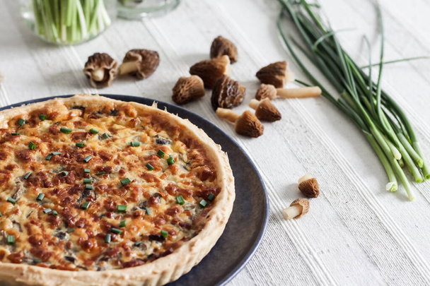 Quiche - open tart pie with morel mushrooms, onion and cheese on a plate - Photo, Image
