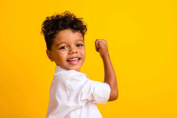 Portrait of pleasant funny schoolboy with wavy hair wear stylish shirt scream yes clenching fist isolated on yellow color background. - Fotó, kép