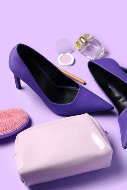 Stijlvolle hakken, cosmetica, tas en haarborstel op lila achtergrond, close-up - Foto, afbeelding