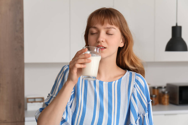 Молодая женщина пьет молоко на кухне
 - Фото, изображение