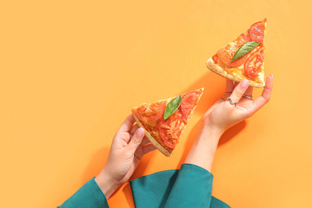 Nainen, jolla on viipaleita maukasta pizzaa oranssilla taustalla - Valokuva, kuva