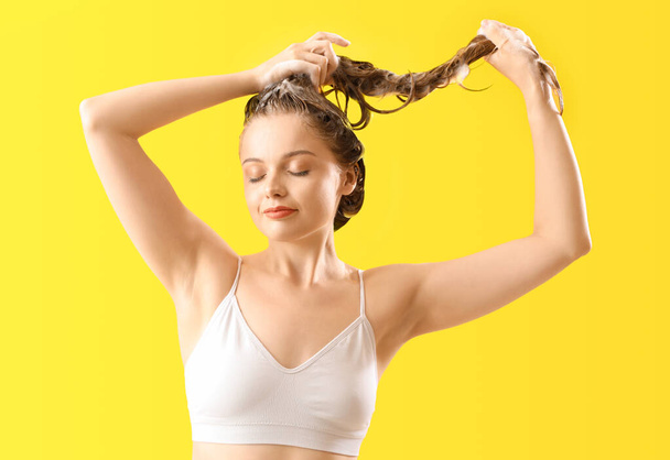 Jeune femme laver les cheveux sur fond jaune - Photo, image