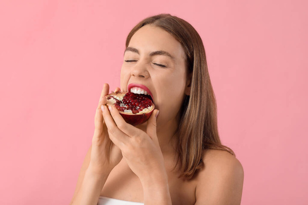 Junge Frau isst Granatapfel auf rosa Hintergrund - Foto, Bild