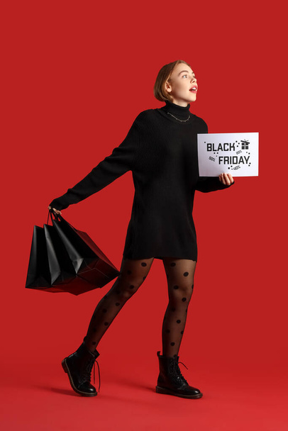 Young woman with shopping bags and card on red background. Black Friday sale - Foto, imagen