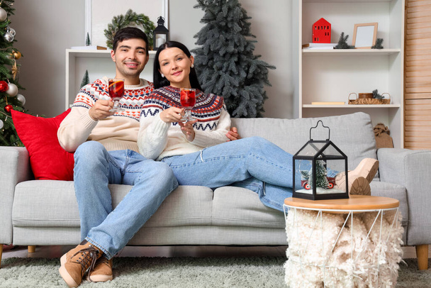 Νεαρό ζευγάρι με ποτήρια κρασί στο σπίτι παραμονή Χριστουγέννων - Φωτογραφία, εικόνα
