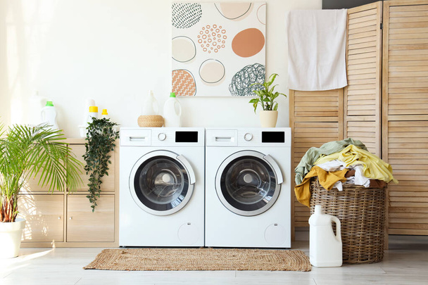Innenraum der Waschküche mit Waschmaschinen und schmutziger Kleidung - Foto, Bild