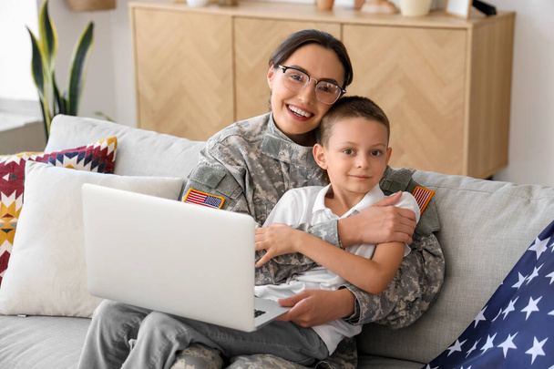 Female soldier with her little son and laptop at home - Photo, Image