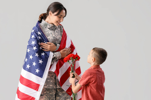 Chlapec zdraví svou vojenskou matku na světlém pozadí. Slavnost Dne veteránů - Fotografie, Obrázek