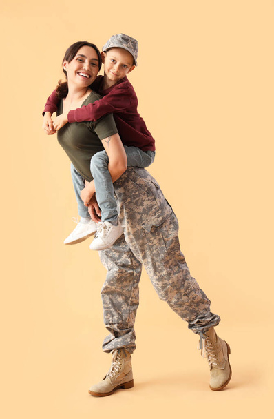 Menino com sua mãe militar em fundo bege. Celebração do Dia dos Veteranos - Foto, Imagem