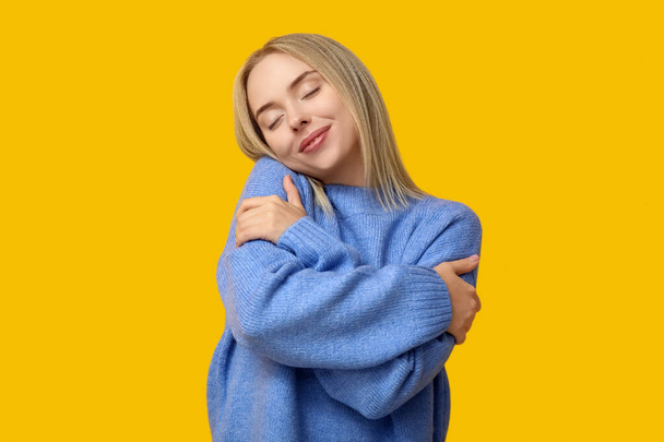 Young woman hugging herself on yellow background - Fotoğraf, Görsel