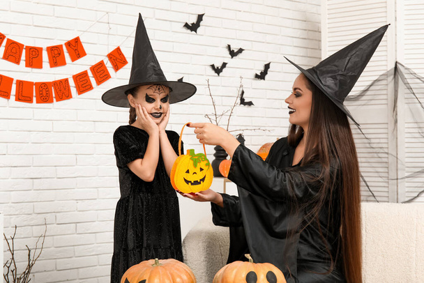 Dziewczynka z matką przebrana za czarownice świętuje Halloween w domu - Zdjęcie, obraz