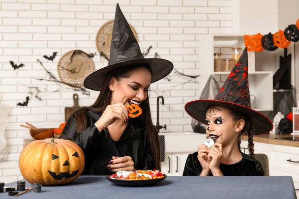 Klein meisje met haar moeder en Halloween traktaties in de keuken - Foto, afbeelding