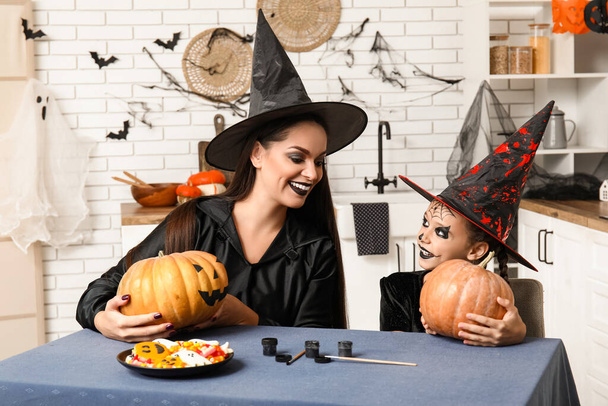 Malá dívka s její matkou malování Halloween dýně v kuchyni - Fotografie, Obrázek