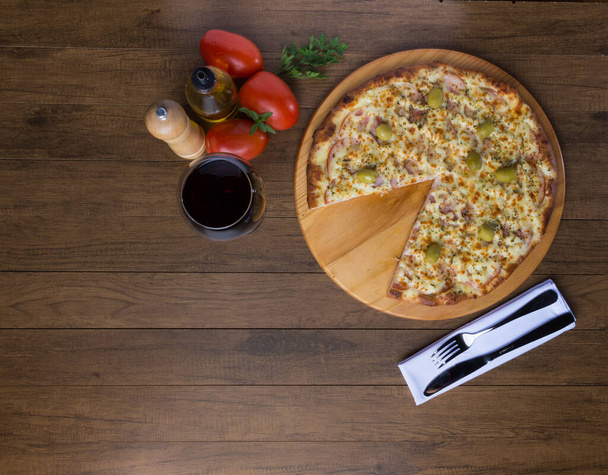 Gratin Sirloin Pizza servida sobre tabla de madera. Mozzarella, solomillo canadiense, cuajada cremosa y aceitunas verdes. Rebanada servida. Copa de vino - Foto, imagen