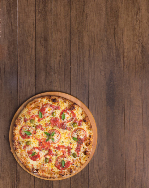 Pizza Marguerita wykonana ze smacznego ciasta pizzowego, Mozzarelli, pomidorów, majeranku i oliwek. Służył na drewnianej desce. Napolitańska pizza. Wyrafinowana gastronomia. Smakosz fotografia pionowy top. - Zdjęcie, obraz