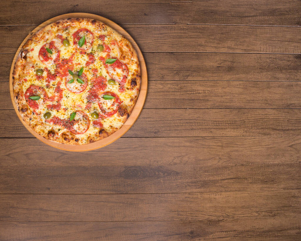 Pizza Marguerita hecha con sabrosa masa de pizza, Mozzarella, tomates, mejorana y aceitunas verdes. Servido en una tabla de madera. Pizza Napolitana. Gastronomía refinada. Fotografía gourmet de la parte superior - Foto, Imagen