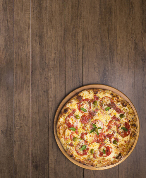 Pizza Marguerita à base de pâte à pizza savoureuse, mozzarella, tomates, marjolaine et olives vertes. Servi sur une planche en bois. Une pizza napolitaine. Gastronomie raffinée. Photographie gastronomique du top 2 - Photo, image
