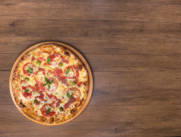 Pizza Marguerita à base de pâte à pizza savoureuse, mozzarella, tomates, marjolaine et olives vertes. Servi sur une planche en bois. Une pizza napolitaine. Gastronomie raffinée. Photographie gastronomique top 3 - Photo, image