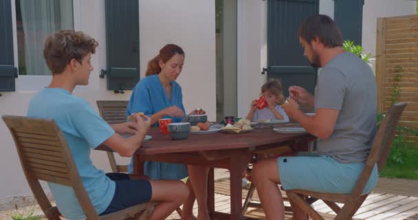 A család nyáron a ház közelében reggelizik. A család, a szeretet és az egység fogalma. - Felvétel, videó