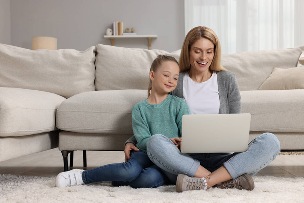 Happy woman and her daughter with laptop on floor at home - Foto, Imagem