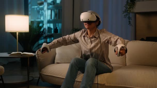 Opgewonden Afrikaanse vrouw spelen virtual reality spel thuis 's nachts gelukkig Amerikaans meisje in gaming simulatie VR helm bril en controllers spelen zwemmen 3D metaverse innovatieve cyberspace technologie - Video