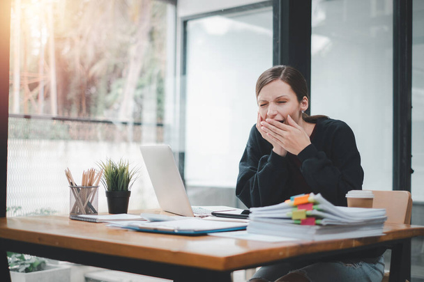 Znudzona bizneswoman ziewanie w miejscu pracy nie czując motywacji lub brak snu zmęczony nudne rutyny biurowej. - Zdjęcie, obraz