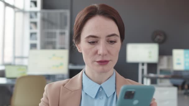 Hrudník se zaměřením na bělošskou podnikatelku pomocí smartphonu na pracovišti v současné kanceláři - Záběry, video