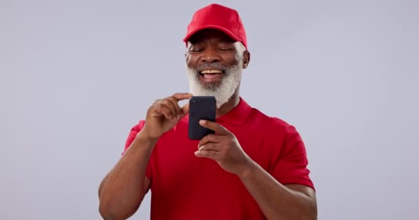 Телефон, смішні та соціальні медіа зі старшим чорношкірим чоловіком у студії на сірому фоні для спілкування. Контакт, посмішка і літня людина сміється в коміксі, мемі або інтернет-пост на своєму мобільному телефоні. - Кадри, відео